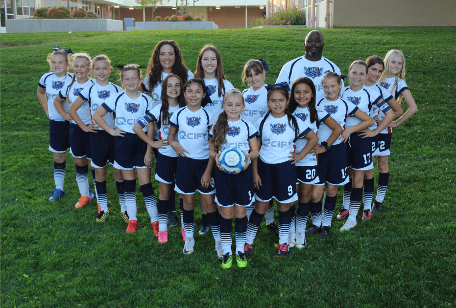 Girls soccer team photo with two coaches on side and 15 fifteen girls in a V-formation wearing QCIFY sponsor on uniform