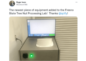 Roger Isom tweet of QCIFY nut processing equipment added to lab with image of equipment machine plugged in with computer monitor on top and green led light indicator on the metal housing body